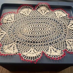 Crocheted doily. Like new. Approximately 22 x 15”. Cream with red trim. Starched